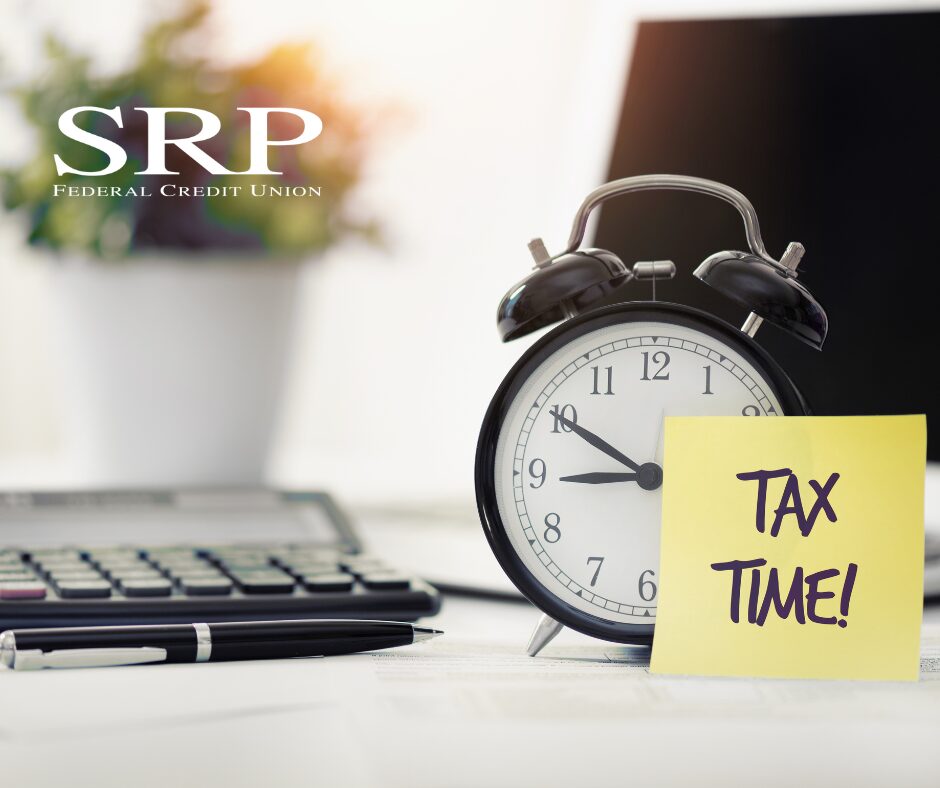 A calculator, pen, and clock next to a sticky note that reads, "Tax Time!"