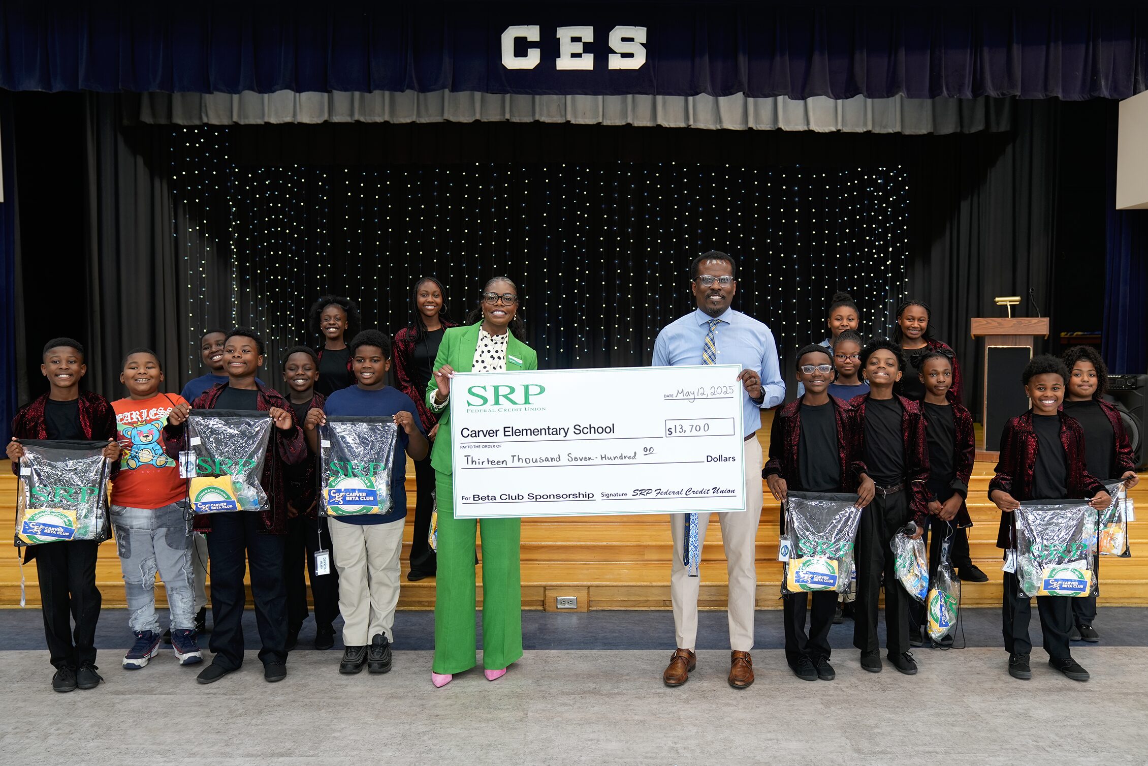 SRP Federal Credit Union Interim CEO Liz Ponder and Carver Elementary School Principal Melvin Farmer, standing alongside members of the Carver Elementary School Beta Club, hold a check sponsoring the club's upcoming trip to Orlando, Florida for the National Junior Beta Convention.