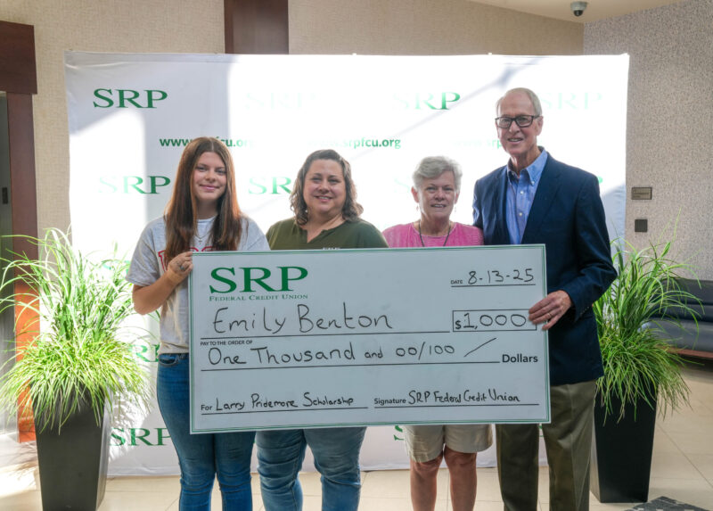Four people hold a ceremonial check.