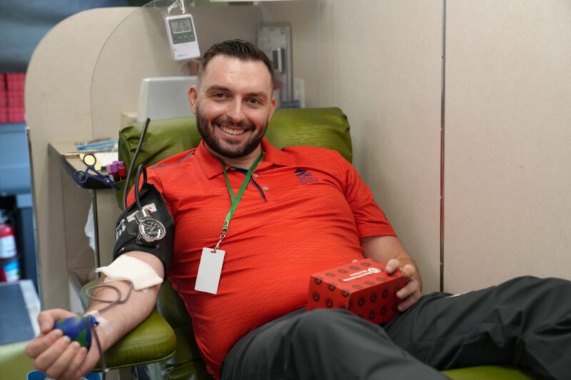 A man donates blood inside a mobile donation unit.