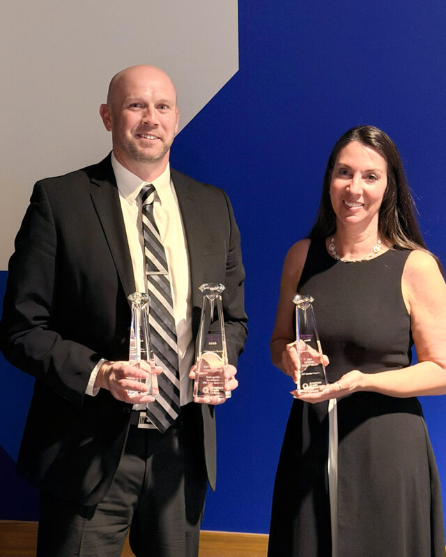 Two business professionals hold Diamond Awards.