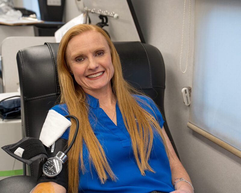 A woman donates blood inside a mobile donation unit.