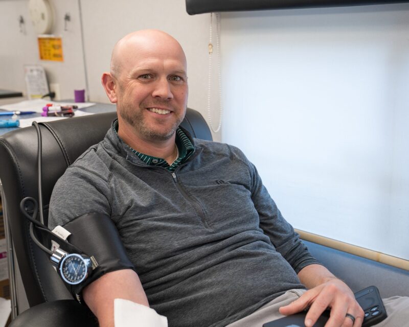 A man donates blood inside a mobile donation unit.