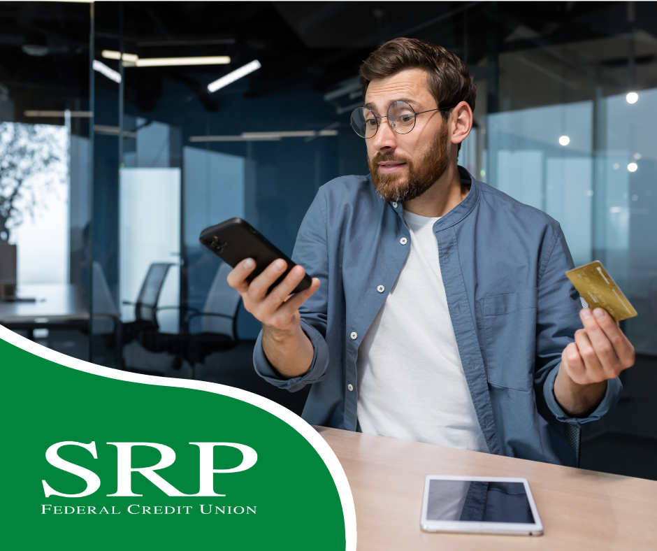 How to protect yourself from credit card fraud A man holds a cell phone and a credit card with a tablet on the table.